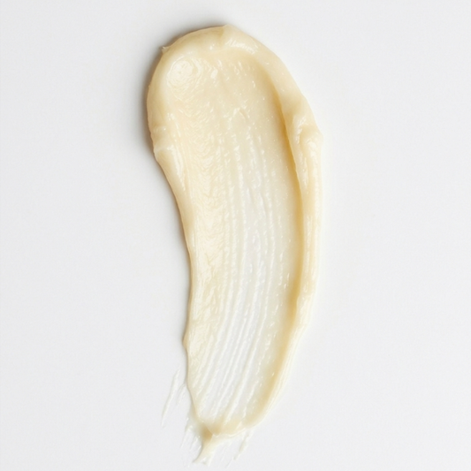 Close-up of a smooth, beige cream swatch on a light gray background
