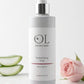 OL Skincare Replenishing Rose Facial Sprayer bottle, styled with pink rose petals, a fresh pink rose, and sliced aloe vera on a white marble slab against a clean white background.