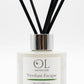 OL Skincare Verdant Escape Reed Diffuser with a white cylindrical bottle, a silver metallic collar, and multiple black reed sticks, shown on a clean white background.